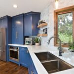 Brightly lit updated kitchen featuring freshly painted navy blue cabinets, modern hardware, stainless steel sink, and clean white countertops as an example of a high-ROI DIY weekend project.